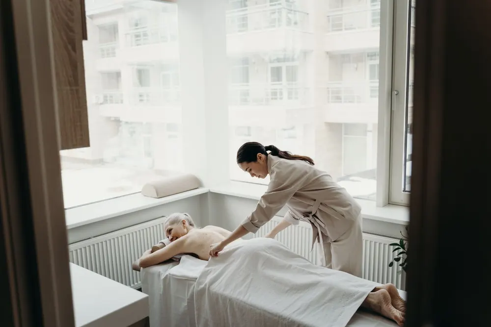 Ljust behandlingsrum med massagebänk vid fönstret